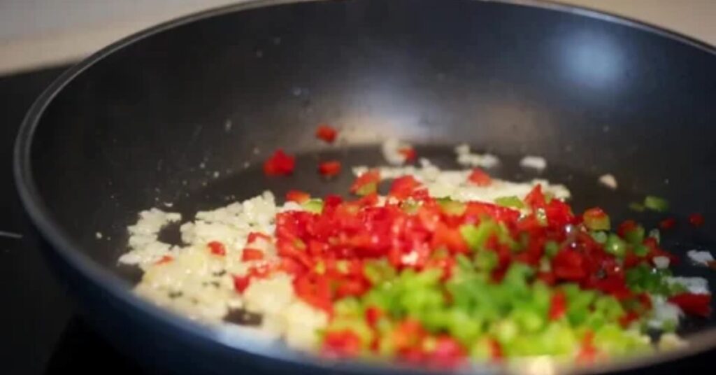 “Cooking vegetables for easy vegetable biryani recipe with onions garlic ginger and tomatoes in spiced oil base”
