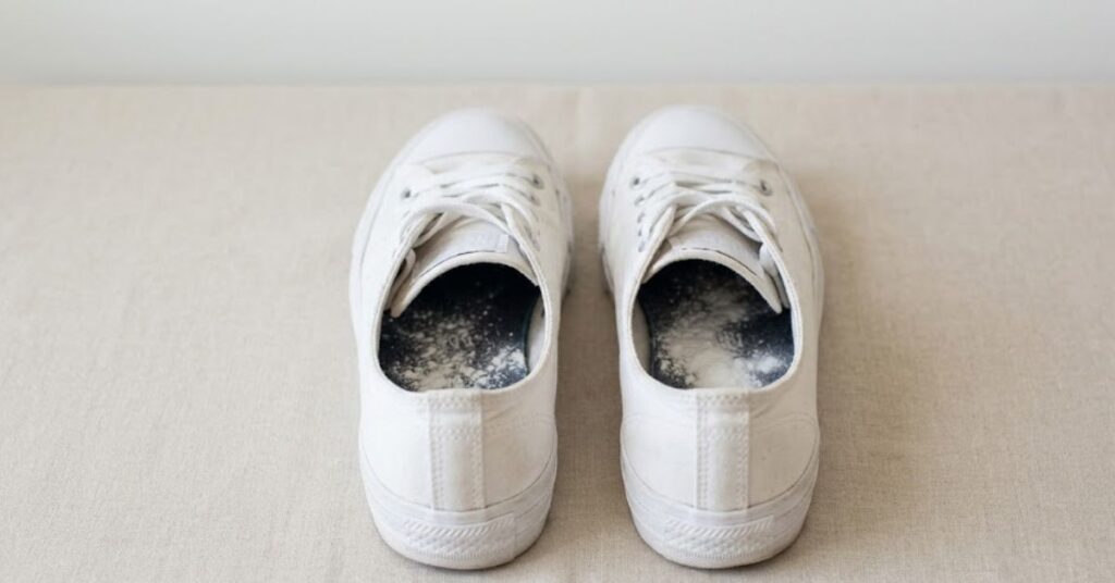 A pair of white sneakers with lavender and a golden tree pebble inside the dusty dark insole.