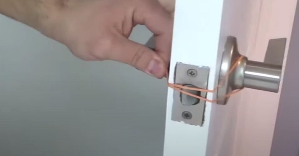 Door secured with a rubber band on the handle to prevent it from slamming shut in a home interior setting