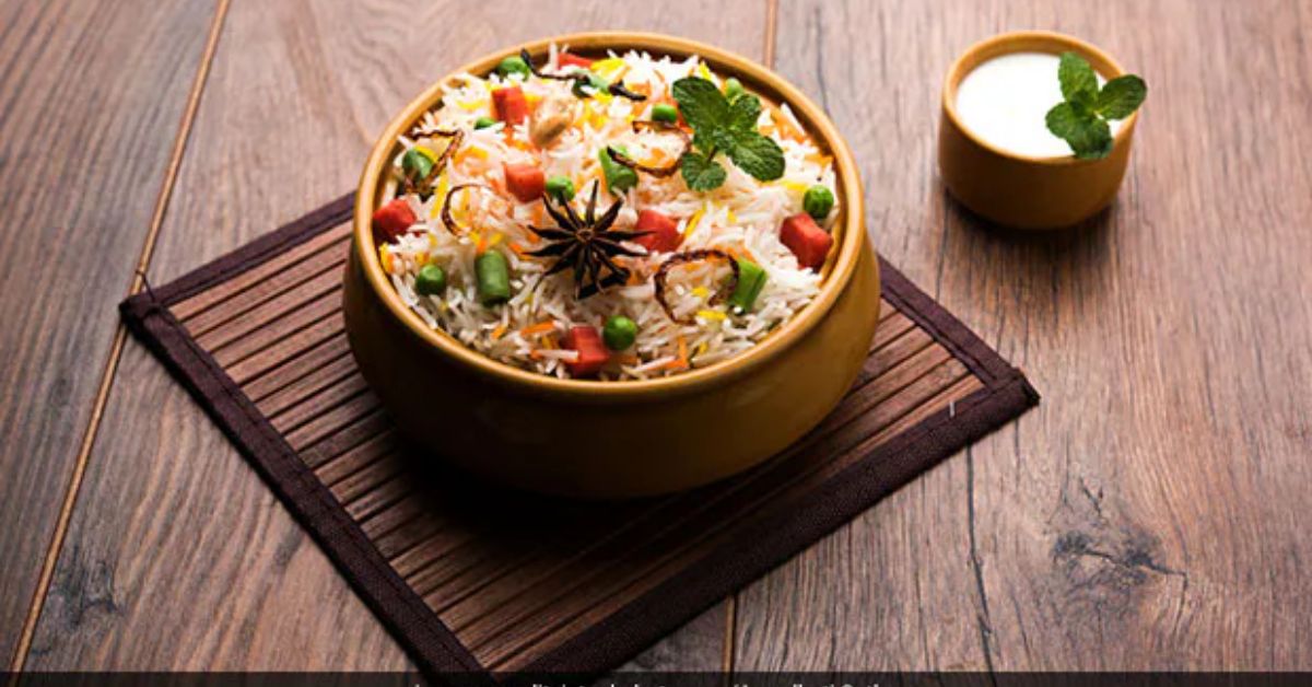 “Finished vegetable biryani recipe garnished with fresh cilantro and mint served hot in a bowl”